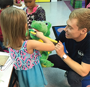 PA student Justin Brewer uses Alexander Alligator to teach a student about brushing in circles.