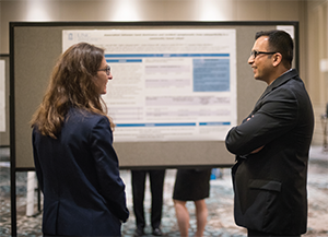 Rheumatology Research Workshop attendees discuss an abstract poster at the poster session and reception.