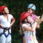 Campers check the ropes before beginning their next challenge.