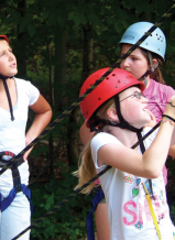 Campers check the ropes before beginning their next challenge.