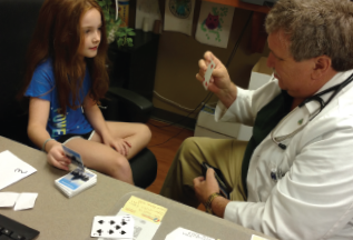 Dr. Morris performs a card trick with Ava Marie Brown, the daughter of colleague and rheumatologist Annette Abril, MD. 