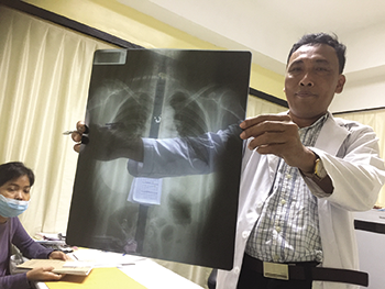 Dr. Rithya, who manages the rheumatology clinic, examines a patient’s X-ray.