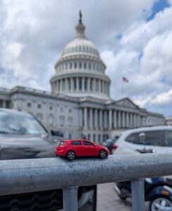 a small red toy car sits on a railing with the US Capitol dome visible in the background