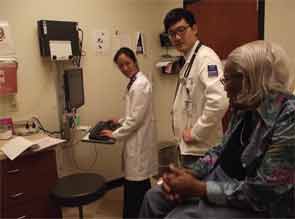 Karen Law, MD (left), treats a patient with one of her medical students.